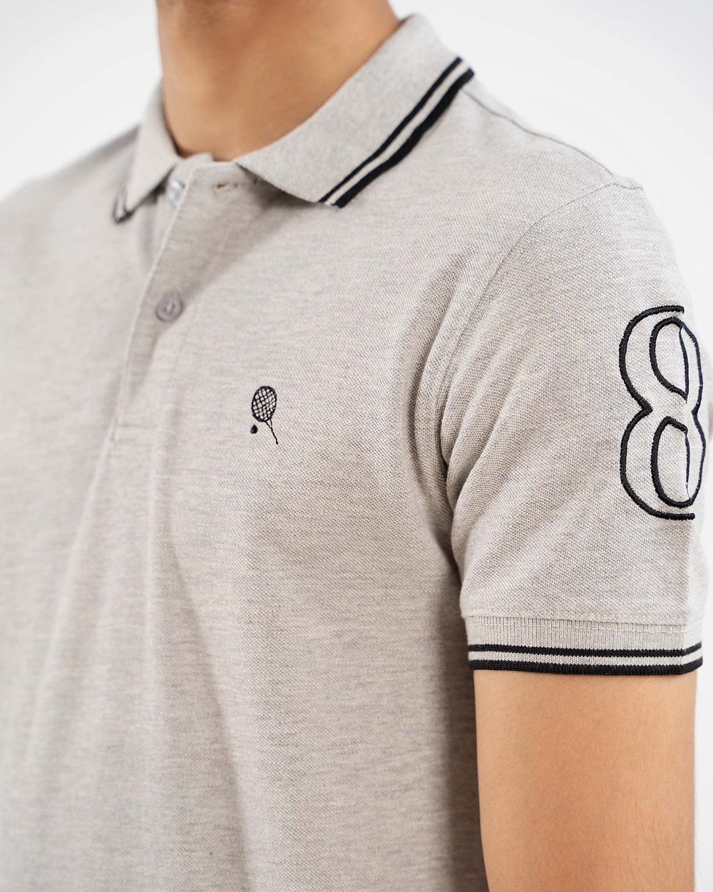 Close-up light grey polo, black tipped collar, crest logo on chest, "8" on sleeve