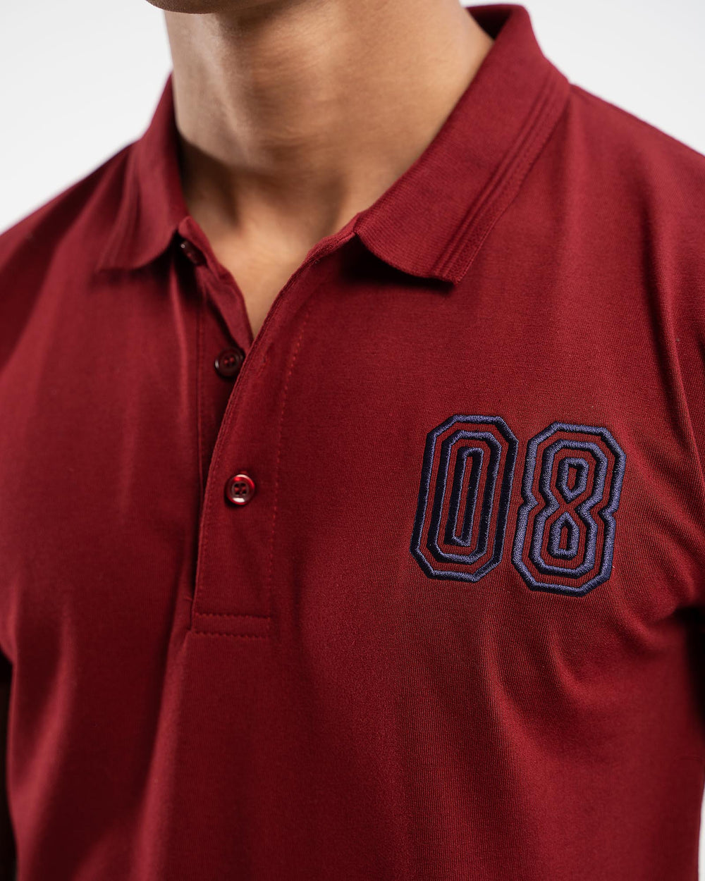 Close-up of maroon polo shirt with embroidered navy blue outlined "08" number on chest