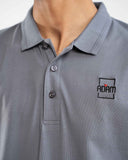 Close-up of grey polo shirt with small embroidered "Adam" square box logo patch on chest