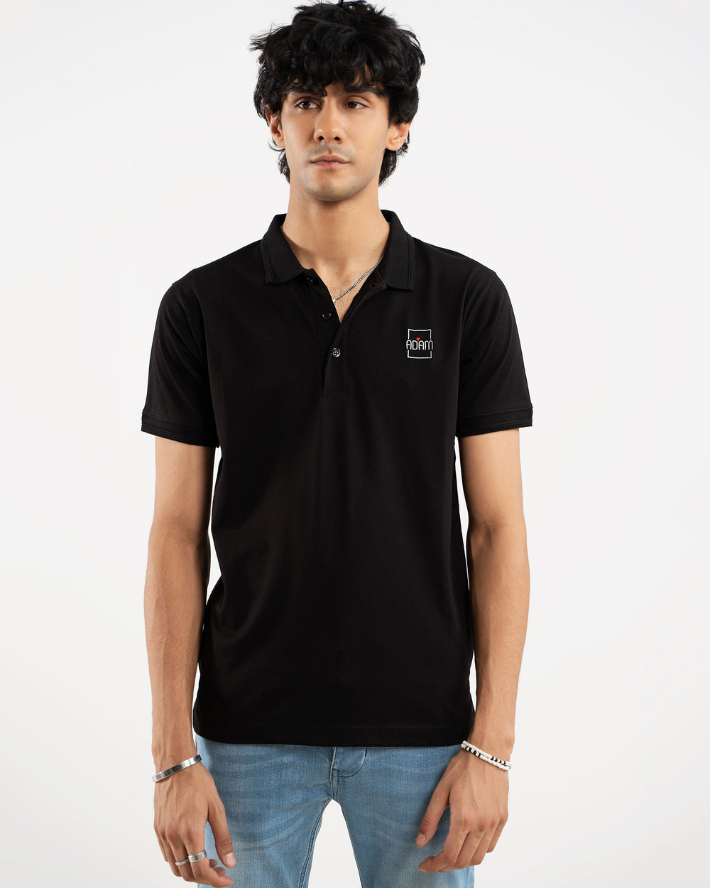 Man in black polo shirt with small embroidered "Adam" square box logo patch on chest, front view