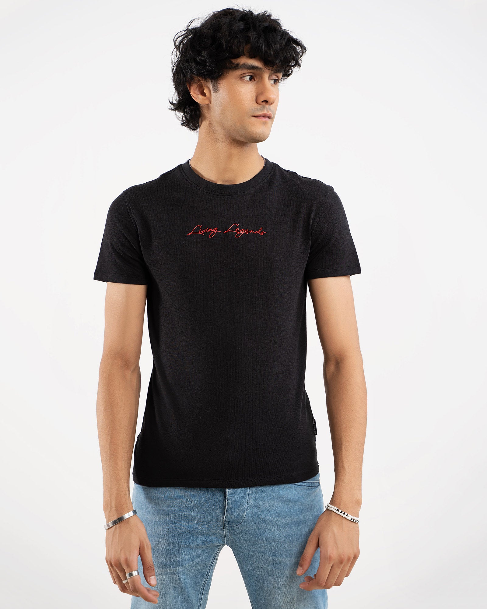 Man in black t-shirt with red "Living Legends" script signature print on chest, front view
