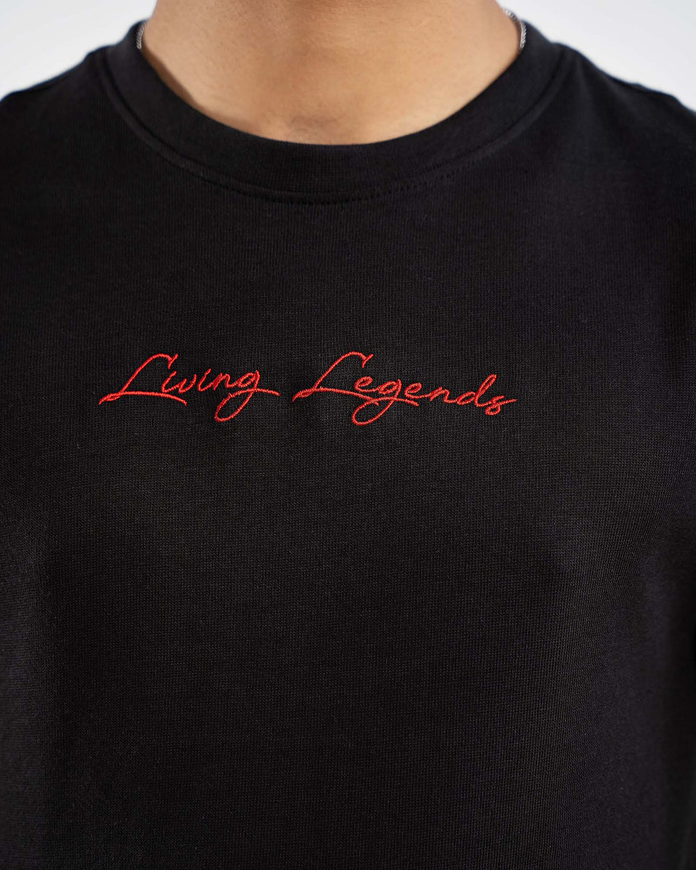 Close-up of black t-shirt with red "Living Legends" cursive signature print on chest