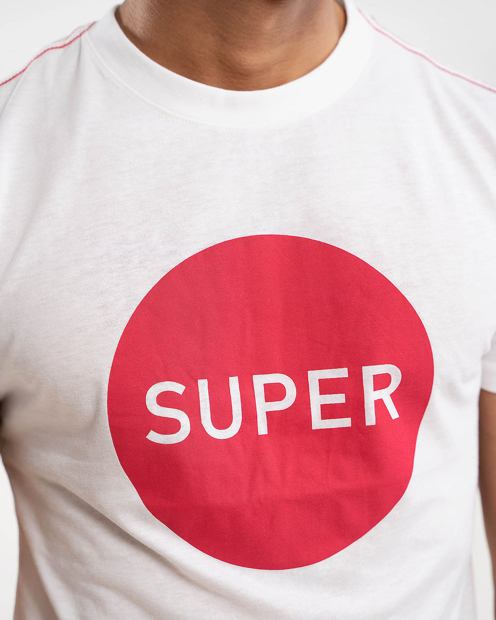 Close-up of red SUPER circle print on white t-shirt chest